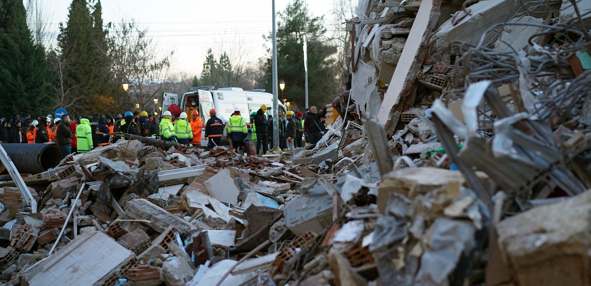 Rescure team members stands behind a collappsed bulding after eathquake